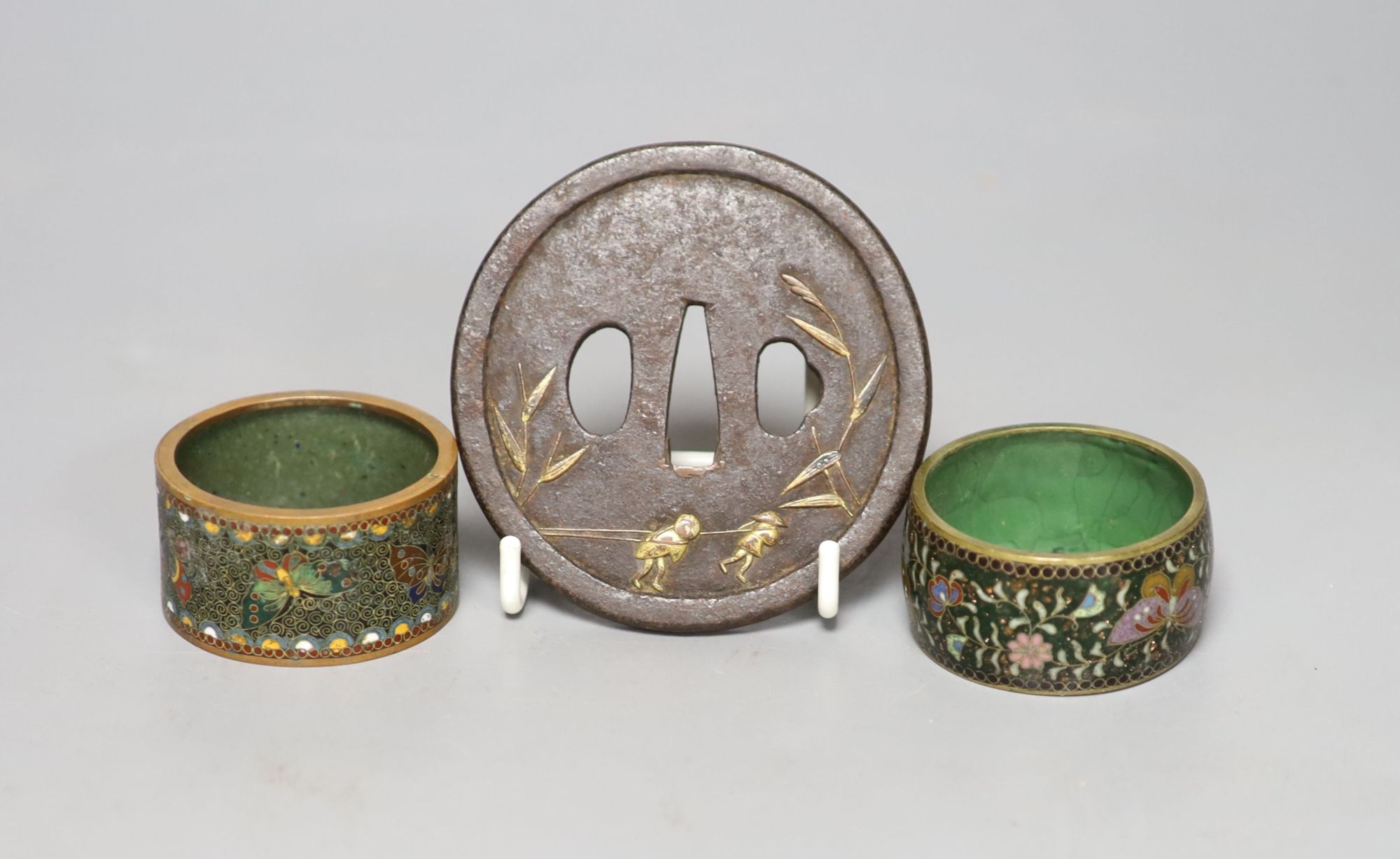 A 19th century Japanese iron and parcel gilt tsuba, unsigned, 8cm and two cloisonne enamel napkin rings.